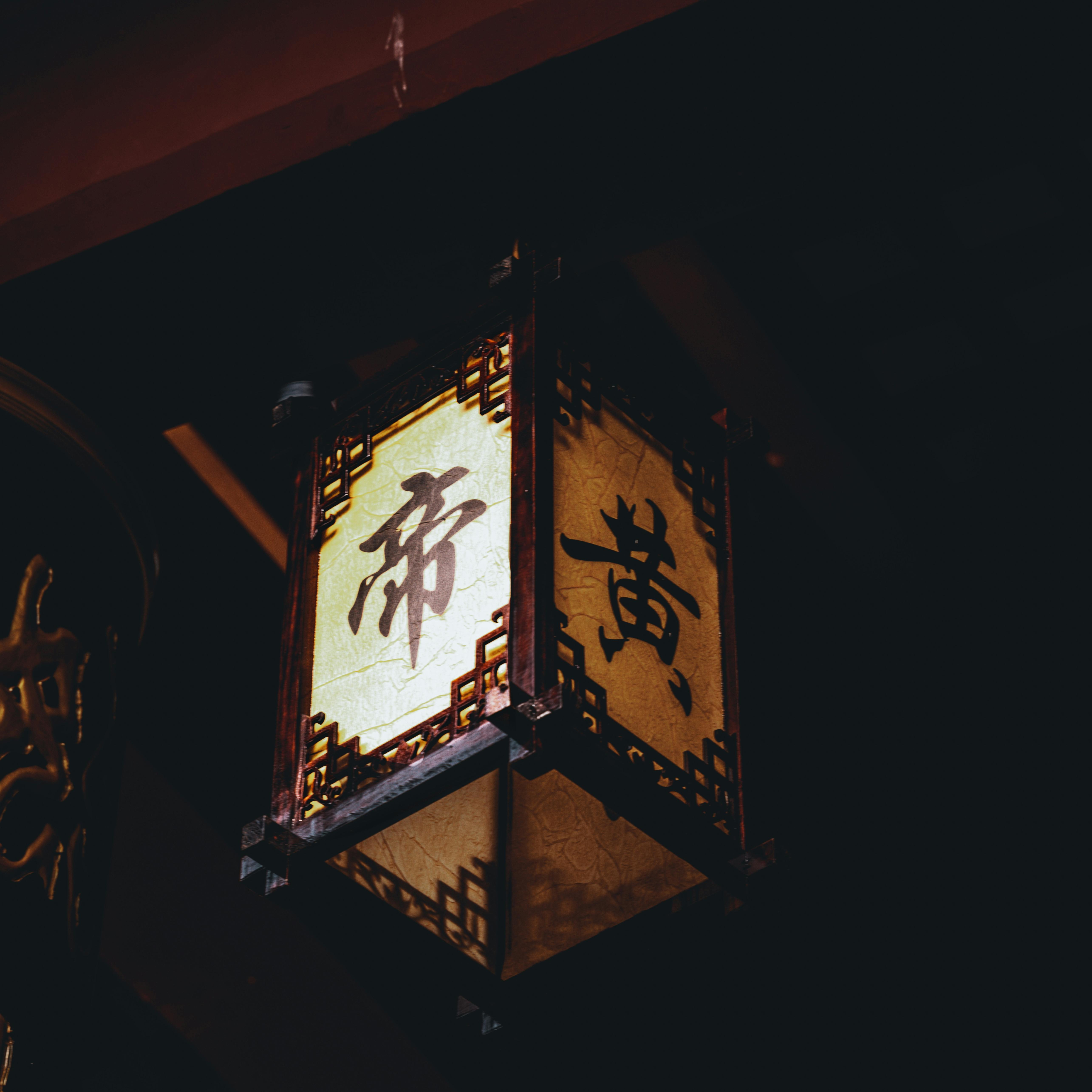 Červený svítící čínský papírový lampion na tmavém pozadí jako symbol výuky asijských jazyků.